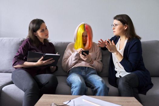 Family mother and teenage daughter in meeting with psychologist. Professional help, support, women are sitting in office on couch. Psychology, therapy, adolescence, relationship parent child teenager