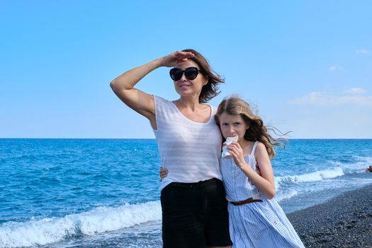 Happy mom and daughter kid hugging together on beach, copy space. Family, vacation, happiness, childhood, mother and child communication