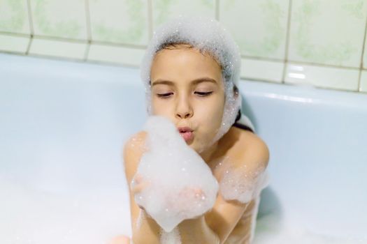 The child bathes in a bathtub soapy water. Selective focus.