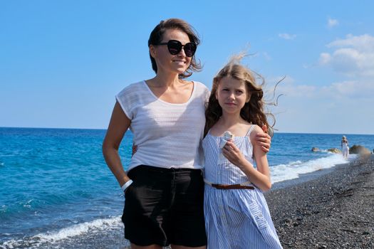 Happy mom and daughter kid hugging together on beach, copy space. Family, vacation, happiness, childhood, mother and child communication