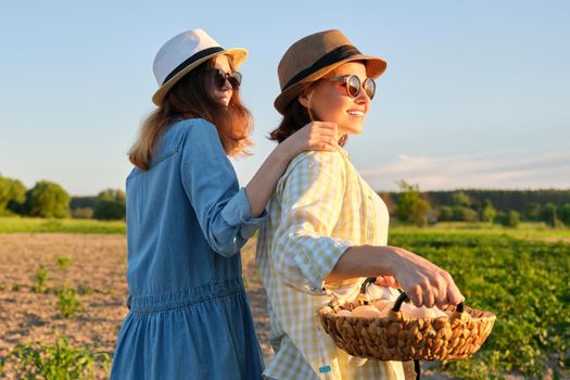 Agriculture, farming organic eco products. Women mother and daughter with basket of eggs, lifestyle, nature, garden, sunset, country side background