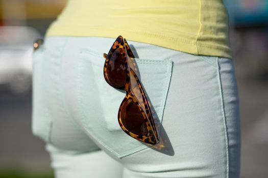 Fashionable Retro style cat-eye Sunglasses in the back pocket of female jeans