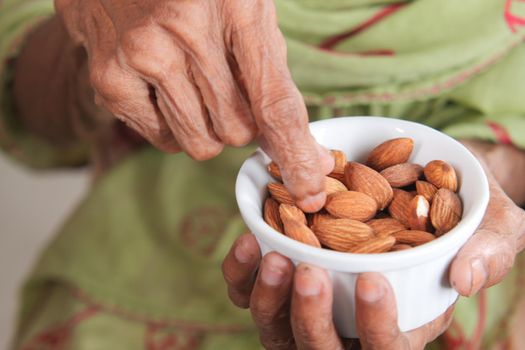 close up senior women hand holding a bowl on almond .