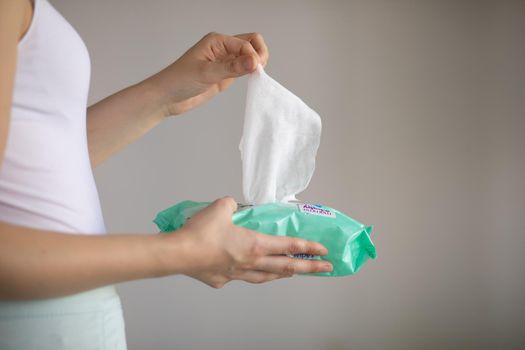 Woman taking wet baby wipes from the packaging - skin care, hygiene procedure and prevention of infectious diseases
