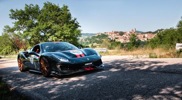 URBINO, ITALY - JUN 16 - 2022 : LAD SCAPE URBINO FERRARI TRIBUTE Ferrari 488 Pista IN an old racing car in rally Mille Miglia 2022