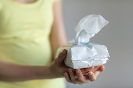 Woman taking wet baby wipes from the packaging - skin care, hygiene procedure and prevention of infectious diseases
