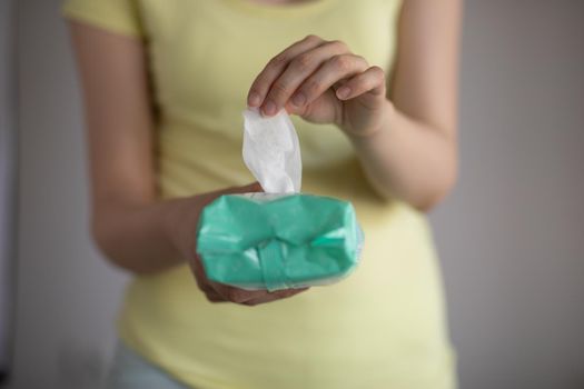 Woman taking wet baby wipes from the packaging - skin care, hygiene procedure and prevention of infectious diseases
