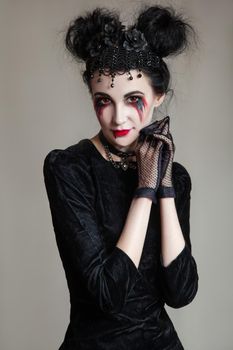 Young beautiful gothic woman with white skin and red lips with bloody drops wearing black collar with spikes. Red smokey eyes. Halloween makeup.