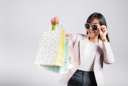 Happy woman with glasses confident shopper smiling holding online shopping bags colorful multicolor, Portrait excited Asian young female purchase studio shot isolated on white background, fashion sale