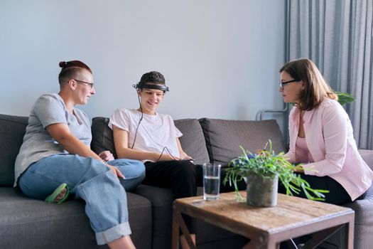 Mother with her teenage son at meeting with social worker, psychologist discussing mental health family sitting on sofa in psychotherapist office