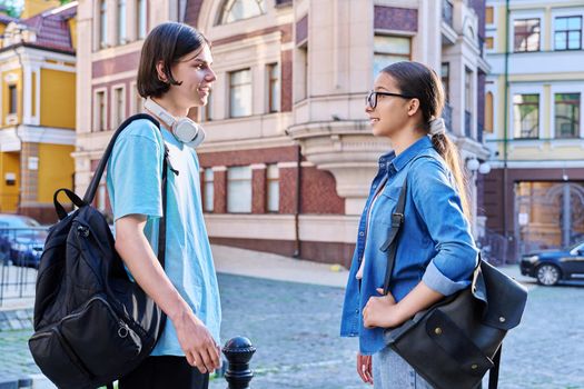 Teenage friends male and female talking on street of city. Fashionable having fun teenagers guy and girl together outdoor. Friendship, communication, holidays, lifestyle, youth, urban style