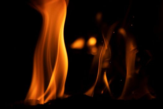 Orange and yellow flame from a campfire dance around as embers burn with a coal black background. Photographed at 1 over 8000 seconds high speed to capture the details of the fire. Canon EOS 90D