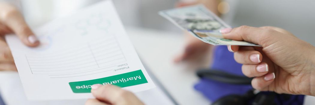 Close-up of patient give banknote money to doctor for marijuana recipe in hospital. Paper with hemp prescription. Alternative medicine, treatment concept