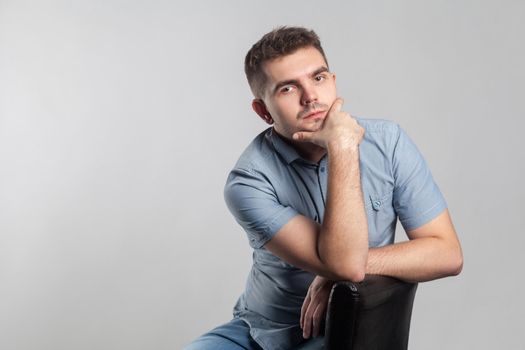 Handsome serious man sit and thinking. Actors portfolio picture, emotion and feelings. Studio shot, isolated on gray background