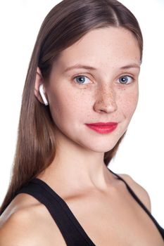 Young beautiful woman with freckles and wireless earphones on her ears. studio shot.