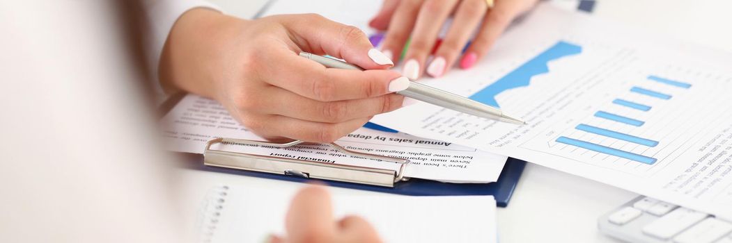 Close-up of female workers discussing working moments and check financial report. Workplace with mess of documents. Business, economy, investment concept