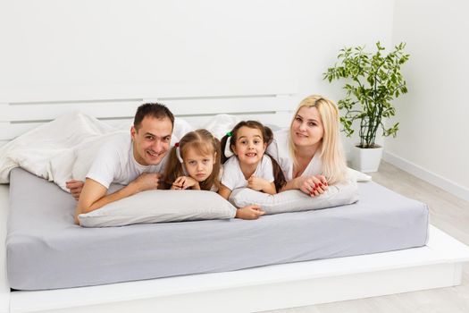 Young family resting together in parent's bed.