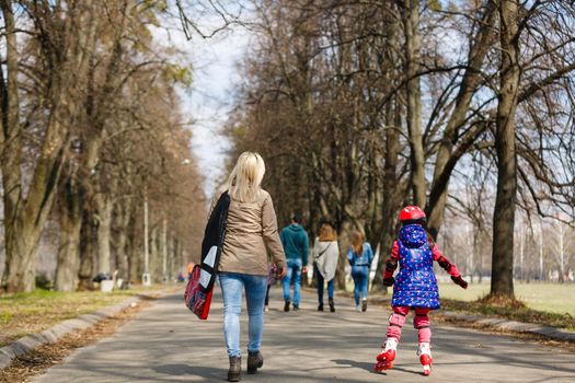 Mother and her daughter wearing roller skates in park.