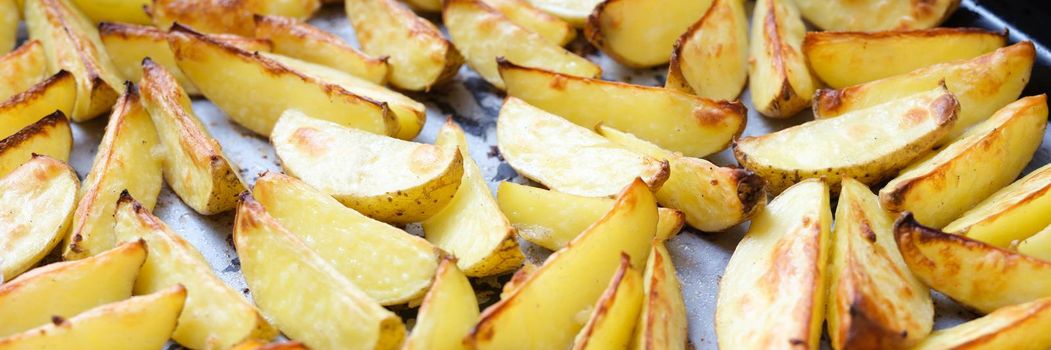 Baked potatoes lying on cooking paper on baking sheet closeup background. Homemade recipes concept