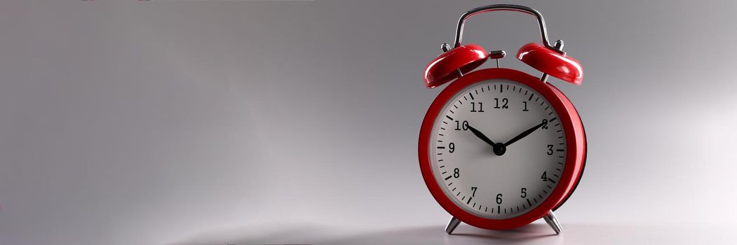 Red classic alarm clock standing on gray background closeup. Work and rest regime concept