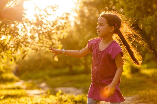 Five years old caucasian child girl blowing soap bubbles outdoor at sunset - happy carefree childhood