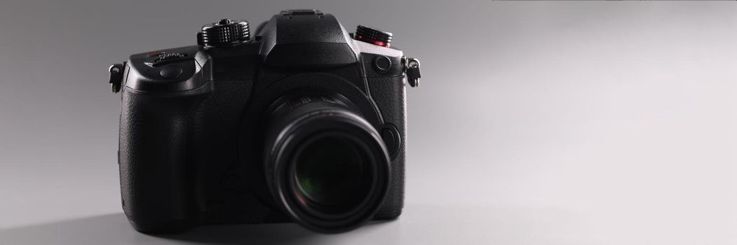 Closeup of black professional camera on gray background. Sale of photographic equipment concept