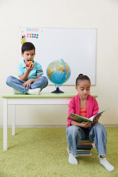 Preschool children playing with books sitting at table