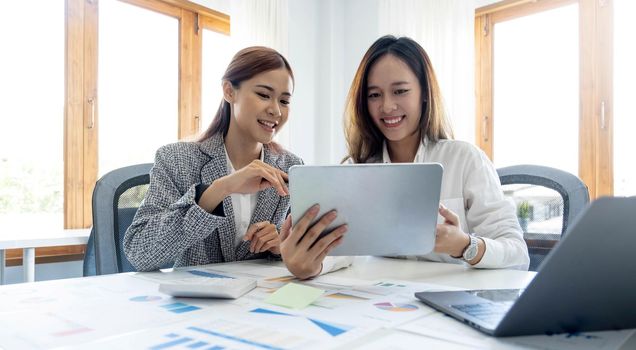 Two beautiful young asian businesswoman working together using digital tablet at office..