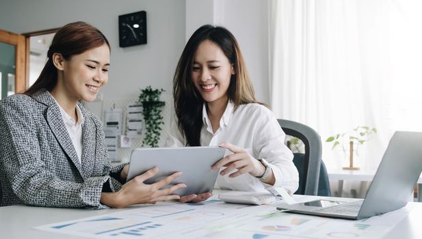 Two beautiful young asian businesswoman working together using digital tablet at office..