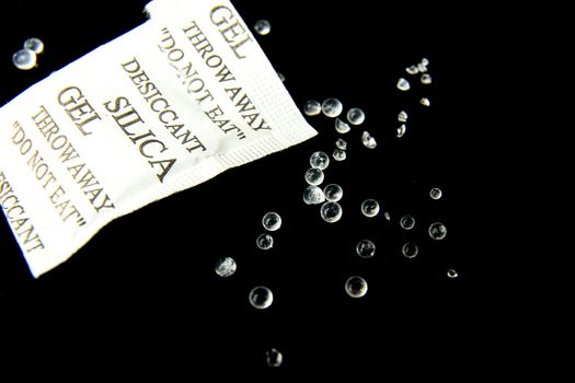 Open packet of Silica Gel Beads on black background. Macro photography.