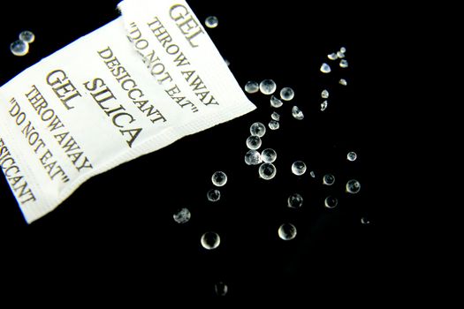 Open packet of Silica Gel Beads on black background. Macro photography.