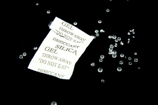 Open packet of Silica Gel Beads on black background. Macro photography.