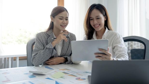 Two beautiful young asian businesswoman working together using digital tablet at office..