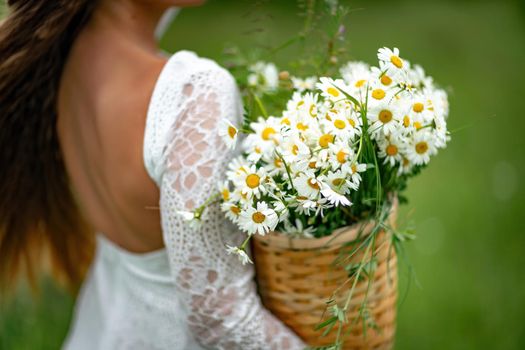 A middle-aged woman holds a large bouquet of daisies in her hands. Wildflowers for congratulations.