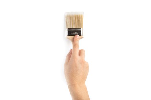 A paint brush in a man's hand. Renovation concept. Supplies and tools for painting walls isolated on white.