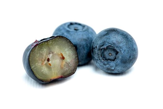 Blueberry isolate on white. Three blueberries on a white background, one blueberry cut in half and the seeds of the berry are visible. Photo for printing or insertion into design