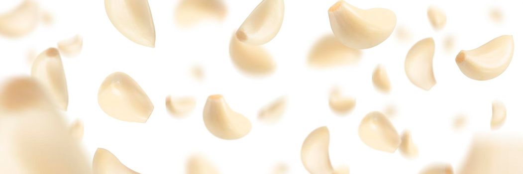 Set of peeled garlic cloves falling on a white background with selective focus. Garlic, isolated on a white background, flies down, casting a shadow