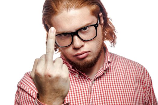 Angry bearded readhead businessman with red shirt and freckles looking at camera and showing middle finger . studio shot isolated on white.