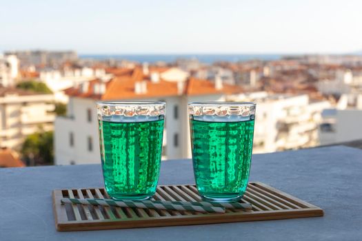 two transparent glasses of Diabolo menthe, popular non-alcoholic cold french drink on the summer sea city background