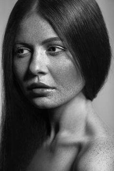 Beautiful fashion model with freckles, makeup and dark hairstyle. .Black and white photography.