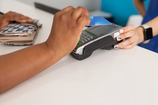 Close up of a black race patient's hand while paying through dataphone for the good service received at the dental clinic