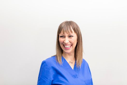 Portrait of a white dentist woman posing and smiling with joy for the camera after a day of work at the dental clinic hall