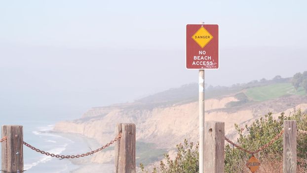 Steep unstable cliff, rock or bluff, foggy weather, California coast erosion, USA. Torrey Pines park eroded crag overlook viewpoint, ocean waves from above. Chain railing. Seamless looped cinemagraph.