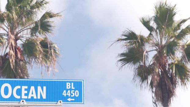 Ocean street road sign on crossroad, California city, USA. Waterfront tourist resort near Los Angeles, beachfront travel destination for waterside summer vacations. Coastal palm trees in La Jolla.