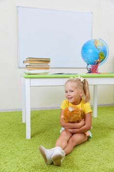 Portrait of cute little latin schoolgirl in classroom. Happy young latin girl in casual clothing