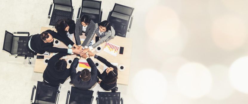 Happy business people celebrate teamwork success together with joy at office table shot from top view . Young businessman and businesswoman workers express cheerful victory in broaden view .