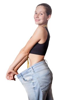 Close-up of slim waist of young woman in big jeans showing successful weight loss, isolated on white background, diet concept.