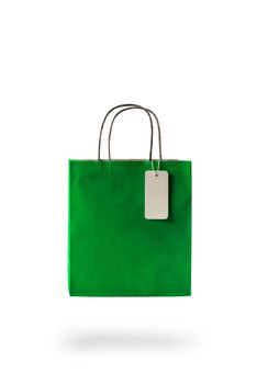 Green color paper shopping bag on white isolated background. An empty price tag hangs to insert text