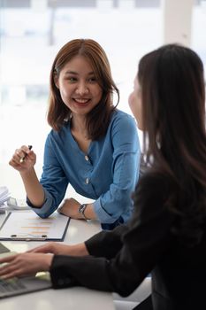 Two business asian female are meeting for analysis data figures to plan business strategies. Business discussing concept.