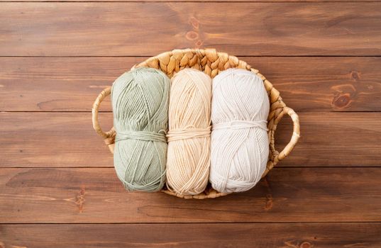 pastel colored yarn wool in a basket on wooden background, top view. Hobbies and leisure. Eco friendly, zero waste